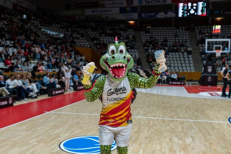 La mascota del Bàsquet Girona a la pista del pavelló de Fontajau amb material promocional de l'Oficina per la Sostenibilitat
