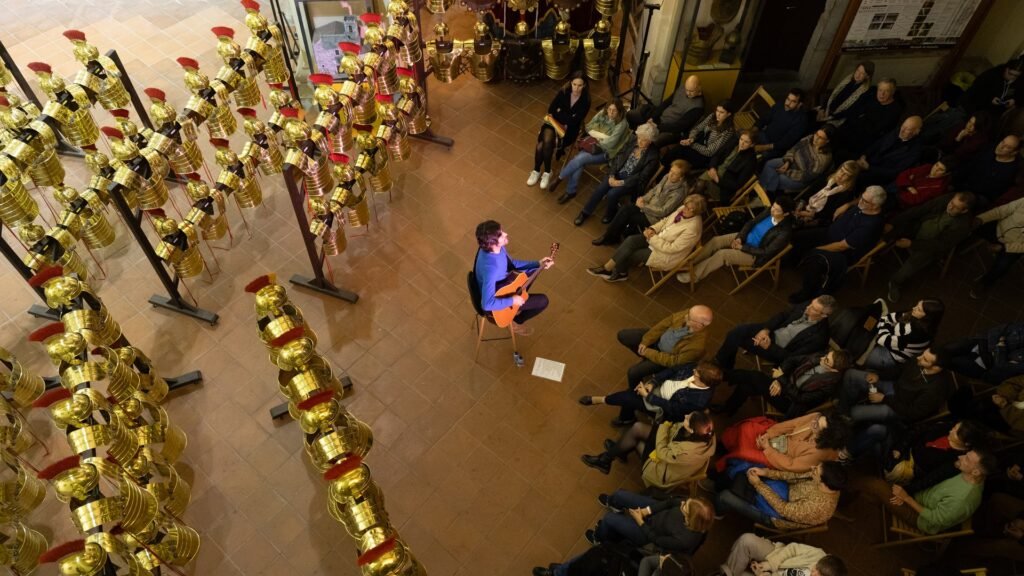 El músic Joan Masdéu toca la guitarra envoltat de públic a l'Església de Sant Lluc de Girona, durant els Concerts a Cegues del 2025