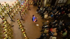 El músic Joan Masdéu toca la guitarra envoltat de públic a l'Església de Sant Lluc de Girona, durant els Concerts a Cegues del 2025