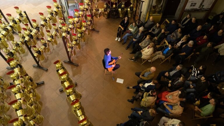 El músic Joan Masdéu toca la guitarra envoltat de públic a l'Església de Sant Lluc de Girona, durant els Concerts a Cegues del 2025